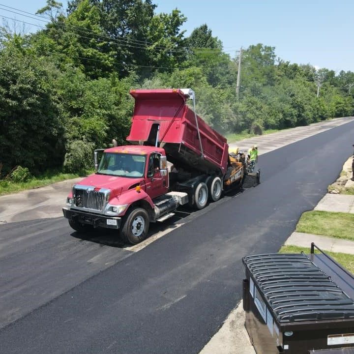 A red dump truck is driving down a road