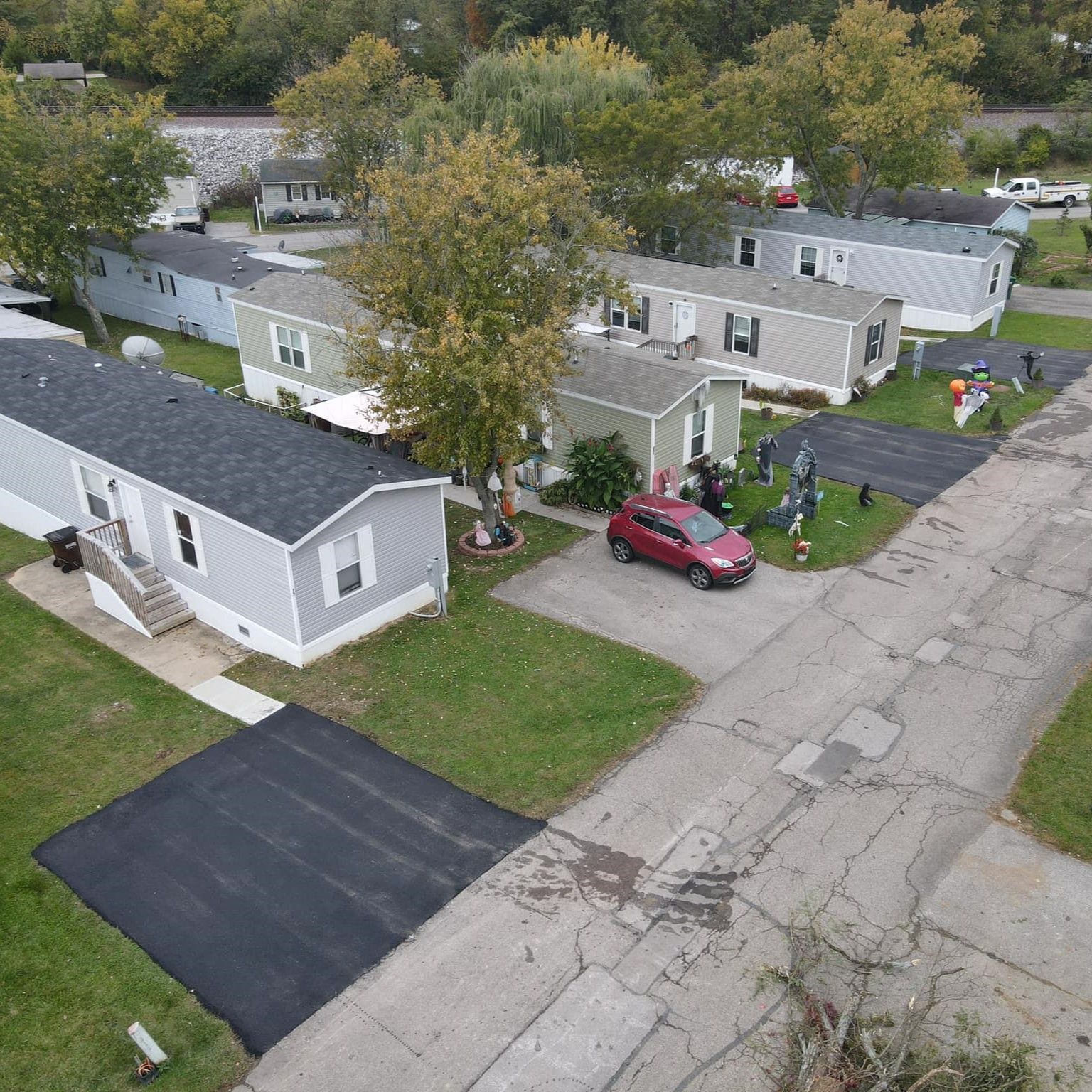 An aerial view of a mobile home park with a red car parked in the driveway. An aerial view of a mobile home park with a red car parked in the driveway.