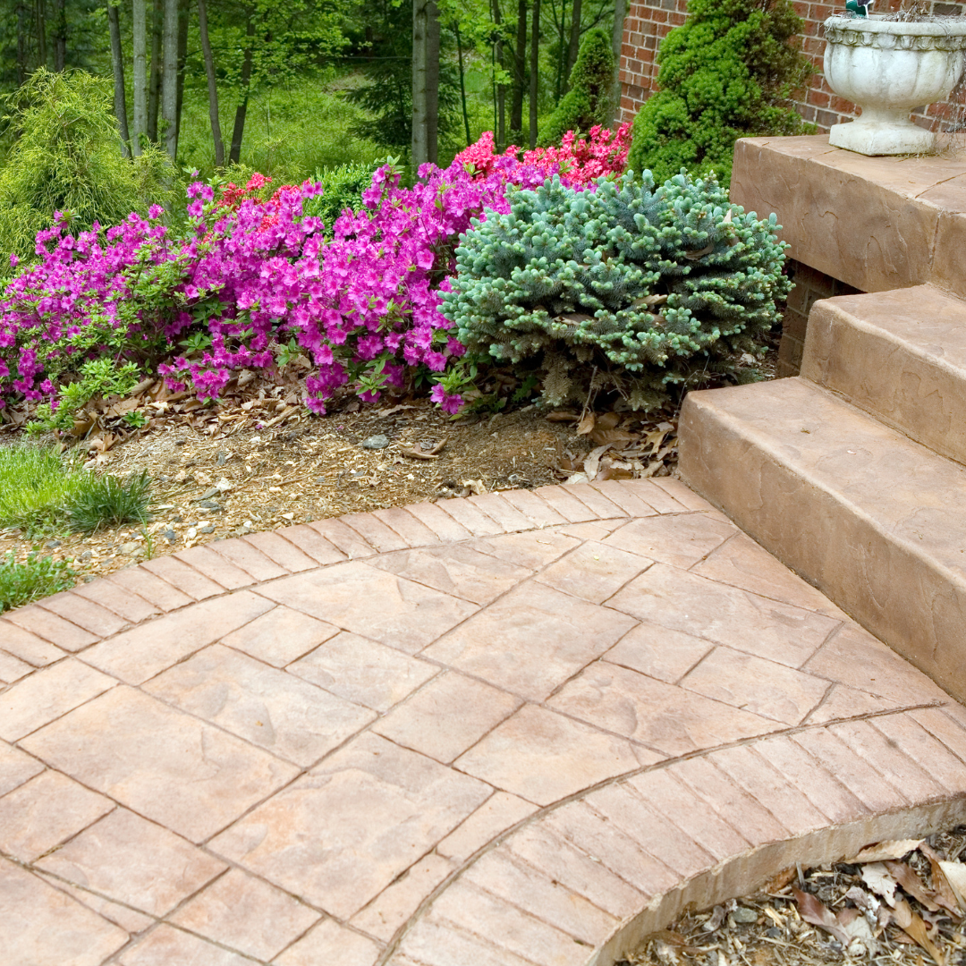 A brick walkway with stairs and flowers in the background