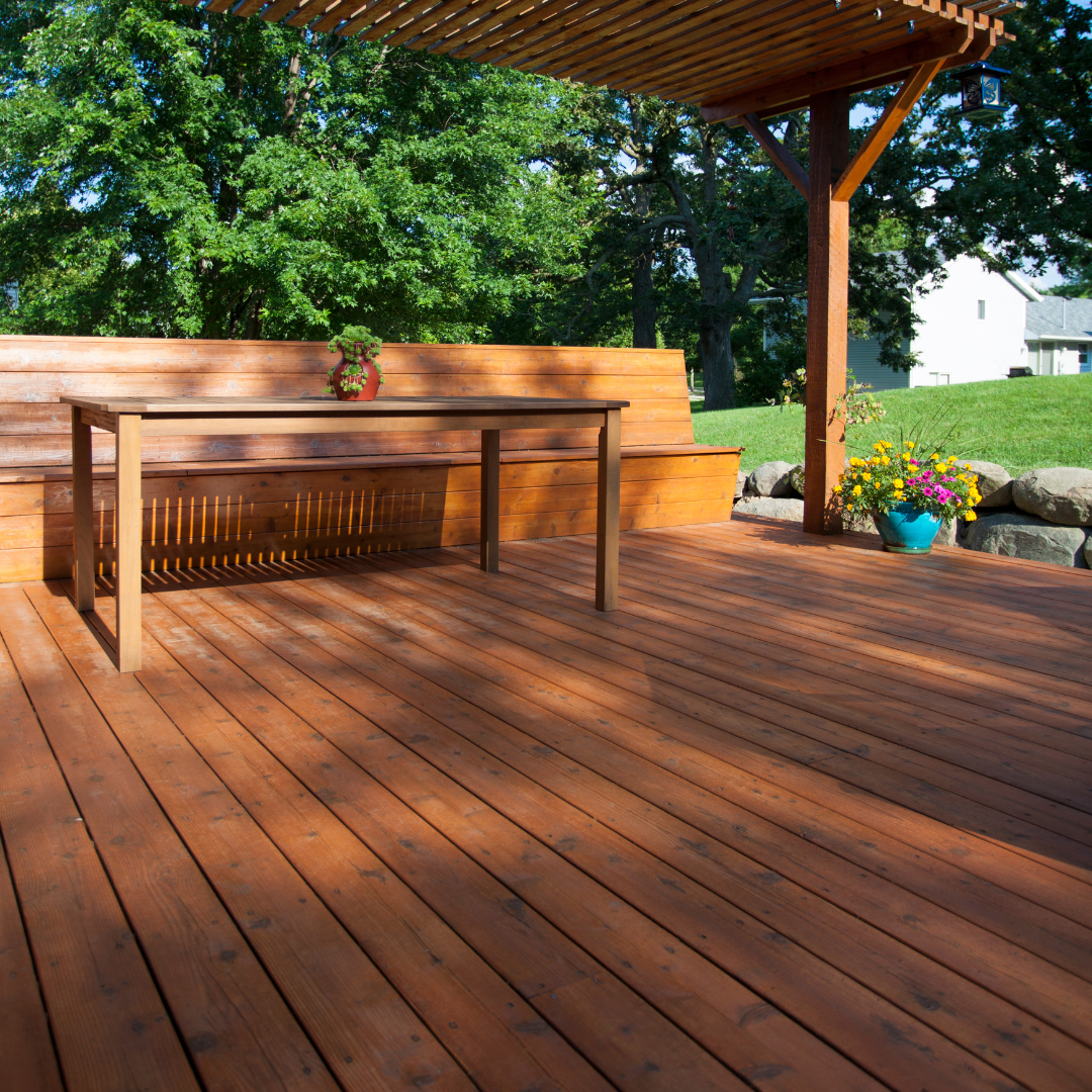 A wooden deck with a table and bench under a pergola