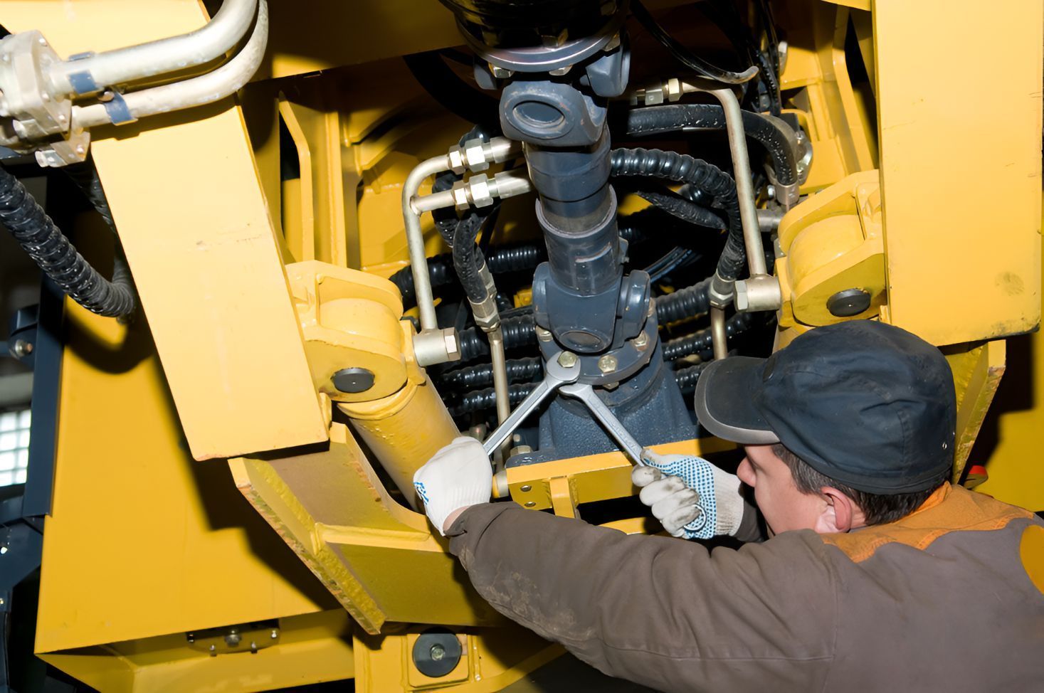 A Man is Working on a Yellow Machine With a Wrench — One Stop Service and Suspension Centre In Port Macquarie, NSW