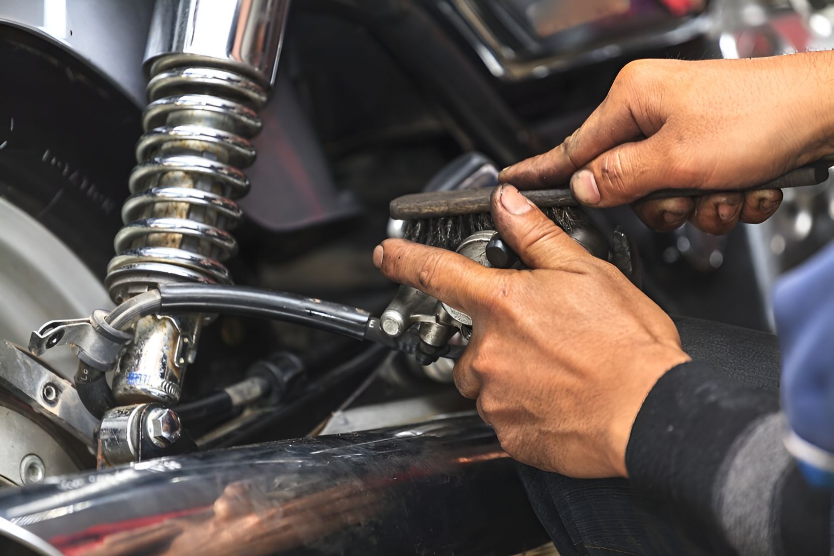 A Person is Working on a Motorcycle With a Wrench and Brush — One Stop Service and Suspension Centre In Port Macquarie, NSW