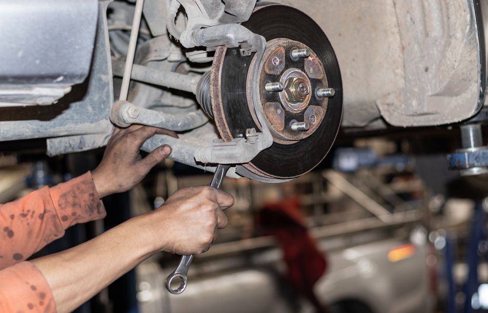 A Man is Working on a Car With a Wrench — One Stop Service and Suspension Centre In Port Macquarie, NSW
