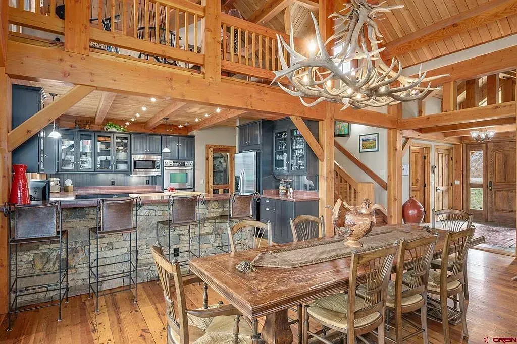 Rustic lodge dining room with wooden beams, chandelier, and bar seating