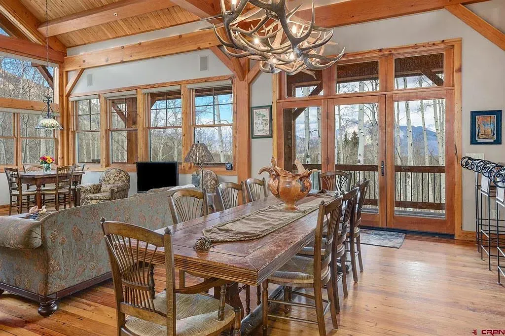 Rustic dining room with a long wooden table, high ceilings, large windows, and lake views