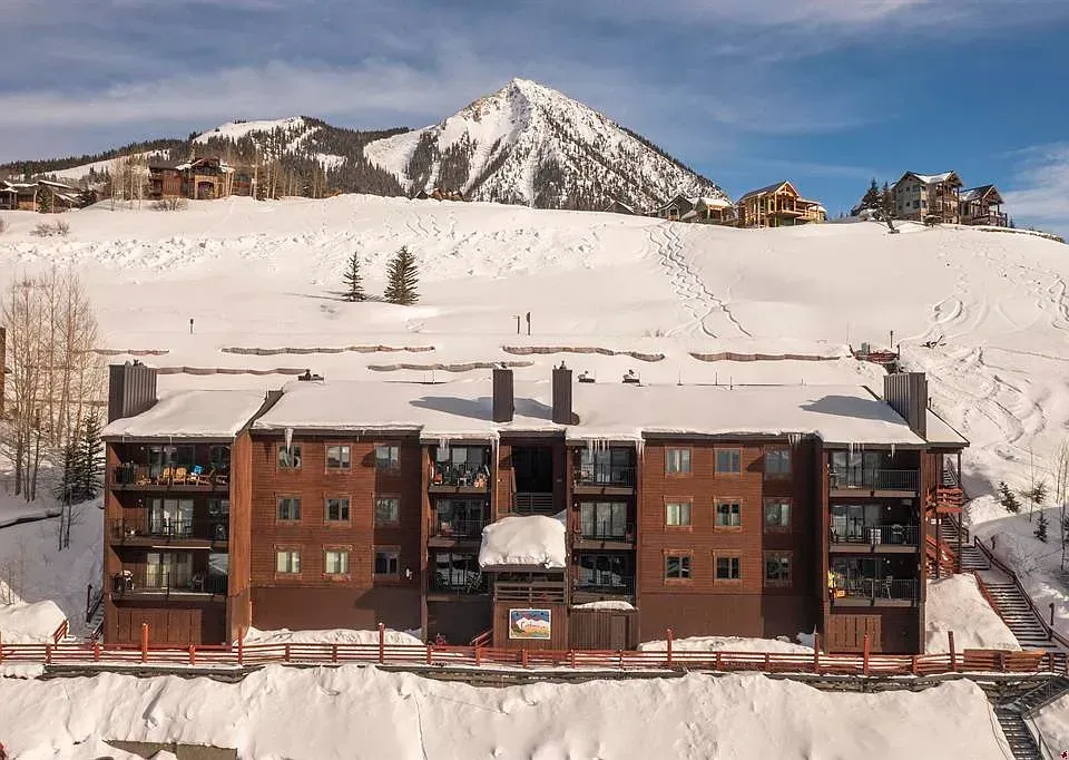 Snowy mountain resort with a brick lodge and ski slope in the background