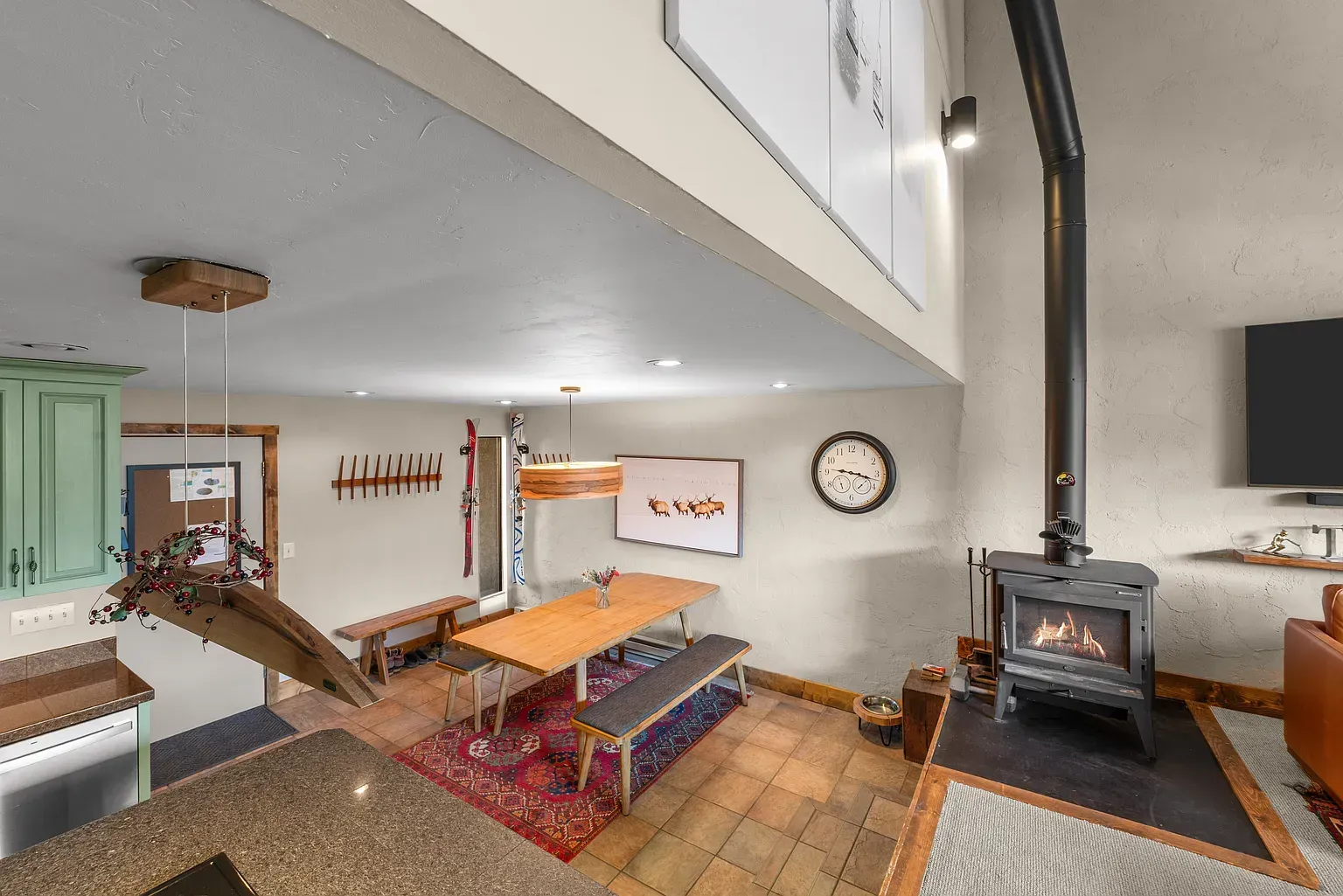 Cozy loft living room with wood stove, couch, armchair, clock, and staircase in a rustic interior