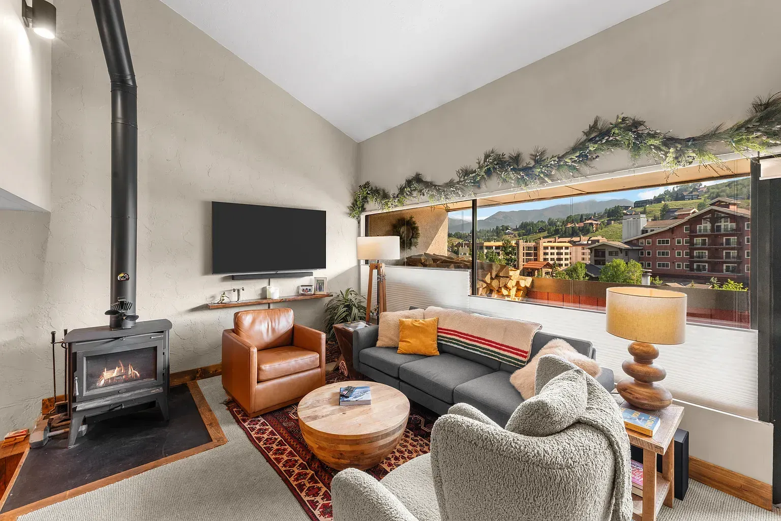 Cozy living room with fireplace, gray sofa, leather chair, and large mountain-view window decor
