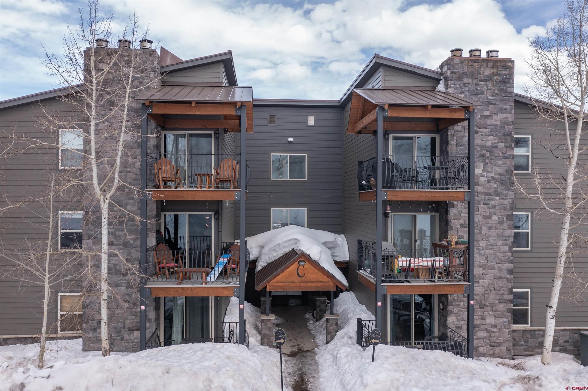 Snow-covered apartment building with balconies and a central covered entrance
