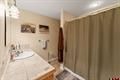 Small bathroom with beige walls, a sink and mirror on the left, and a beige shower curtain on the right.