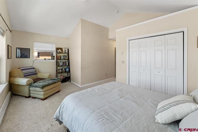 Bright bedroom with bed, armchair, bookshelf, and white closet doors