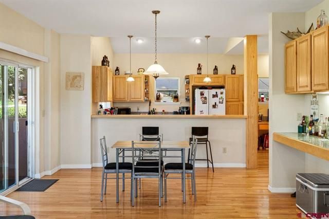 Bright kitchen with wood floors, island, dining table, and sliding glass door to the left