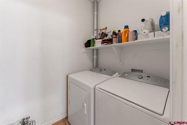 Laundry room with a white washer and dryer under a shelf of cleaning supplies