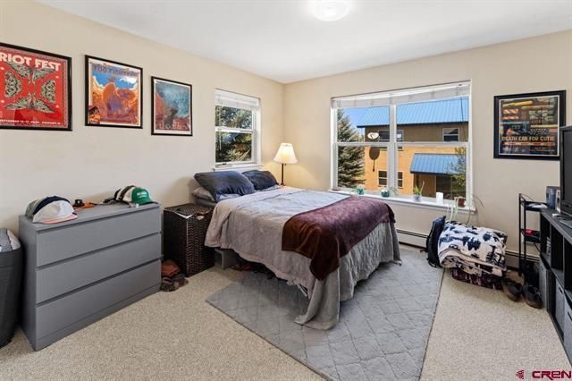 Bright bedroom with bed, dresser, wall art, large window, and gray rug