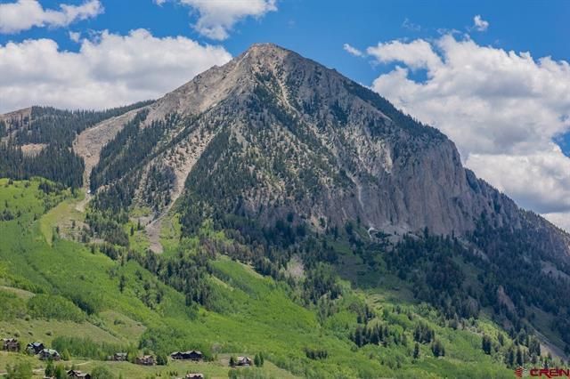 Mountain peak above green alpine hills under a cloudy sky