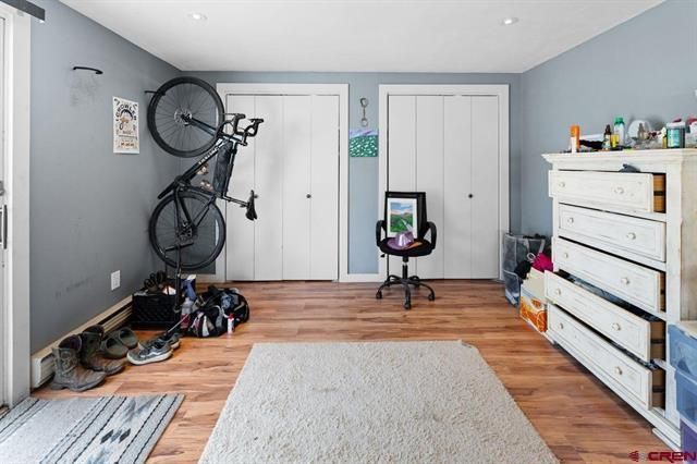 Cluttered bedroom with a bike on the wall, chair, dresser, and clothes scattered on the floor