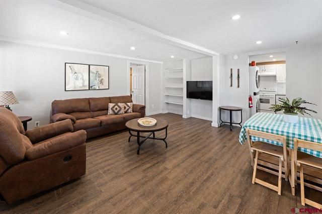 Bright living and dining room with brown sofa, wood floor, TV, and checkered tablecloth