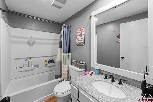 Modern bathroom with shower-tub, toilet, vanity sink, and large mirror