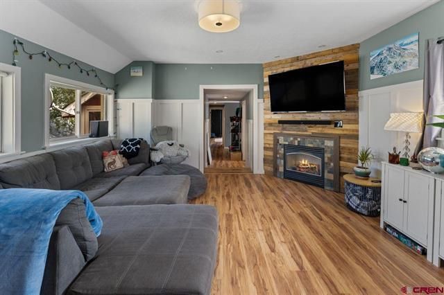Cozy living room with gray sectional, fireplace, wall-mounted TV, and wood floors.