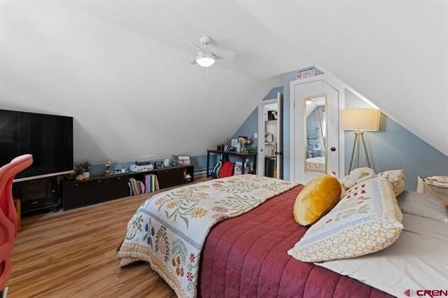Bright attic bedroom with sloped ceiling, bed, TV, lamp, and skylight.
