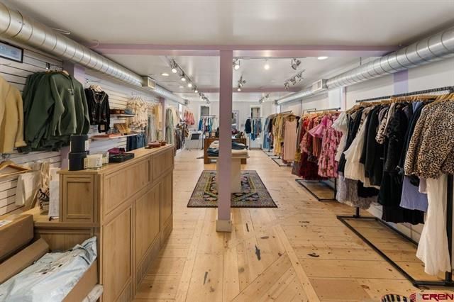 Boutique clothing store interior with wooden displays, racks of apparel, and a central aisle