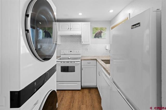 Compact white galley laundry room with stacked washer-dryer, stove, and refrigerator along narrow aisle