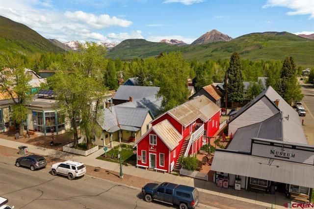 Small mountain town street with colorful shops and houses against green hills under a blue sky