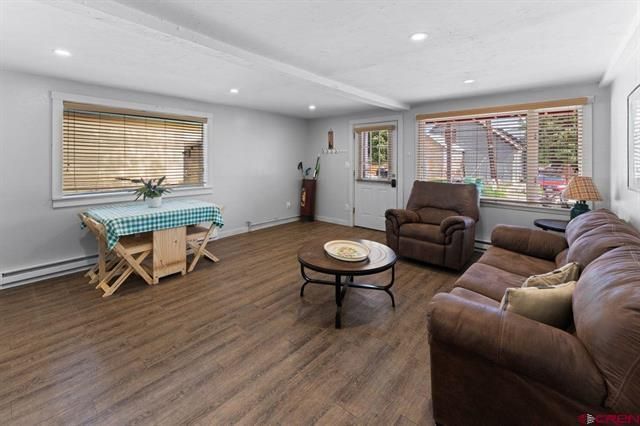 Bright living room with brown sofas, round coffee table, and a small table by a window with blinds.