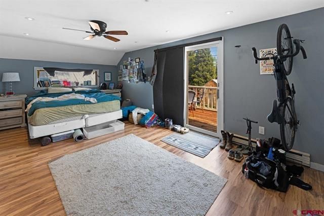 Bedroom with gray walls, teal bedspread, rug, open door, and exercise bike near the wall