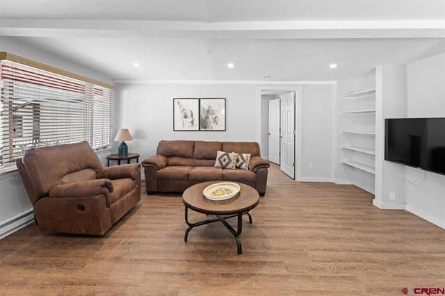 Bright living room with brown recliners, sofa, coffee table, wall art, and TV on a white wall.