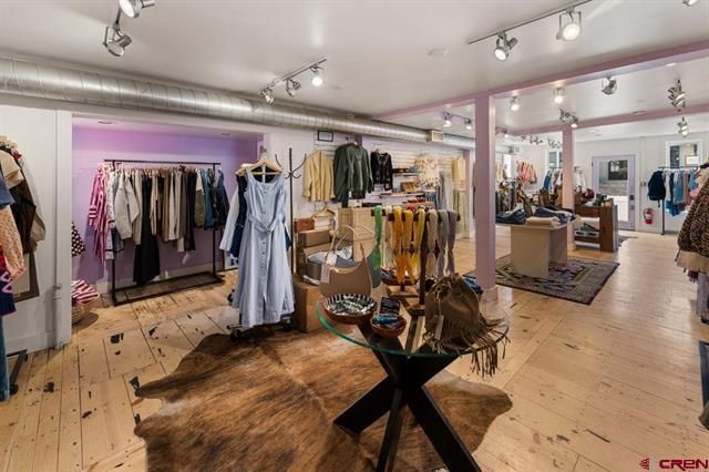 Boutique clothing store interior with racks of dresses and accessories on wood floors