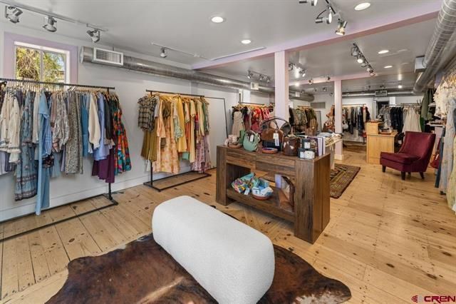 Clothing boutique interior with racks of colorful garments, wooden floors, and display tables