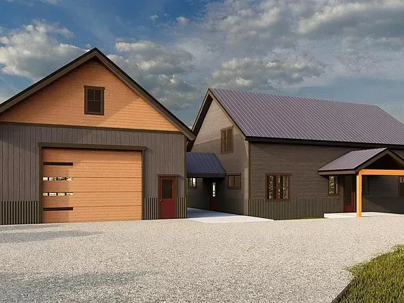 Modern two-story house with garage and gray roof on a gravel lot under a cloudy sky