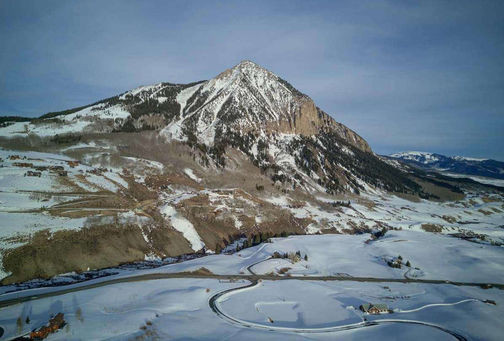 Snow-covered mountain under a cloudy sky, with a frozen plain and circular ice formations in the foreground