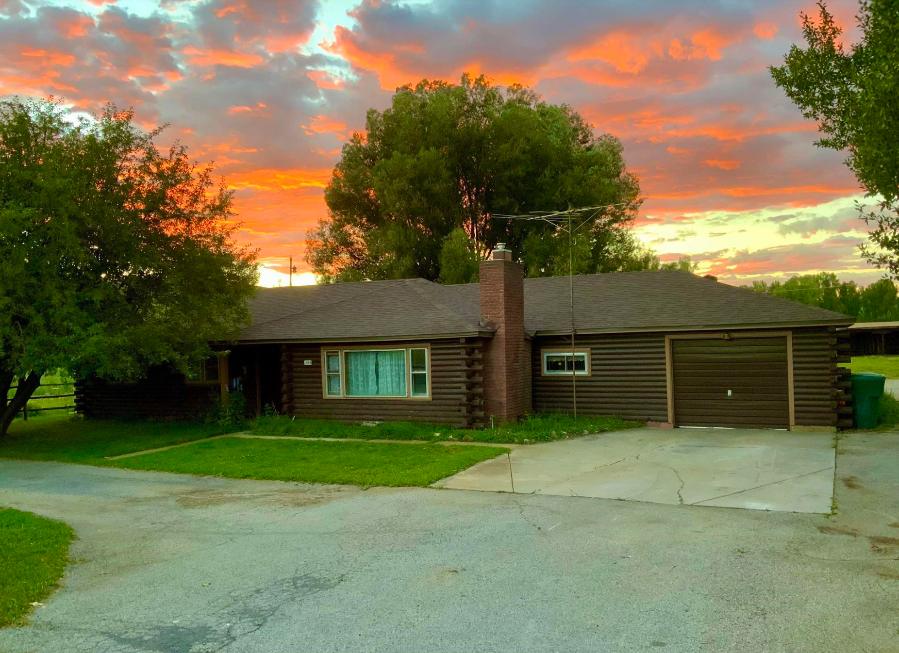 Single-story house with a garage at sunset, under a dramatic orange sky