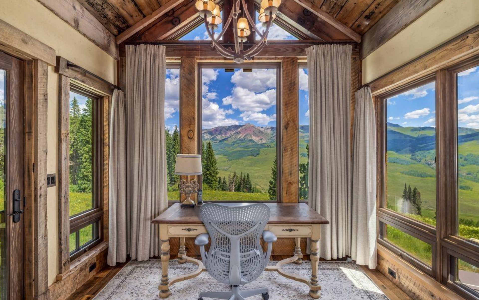 Cozy cabin sitting room with large windows, a chandelier, and mountain views outside
