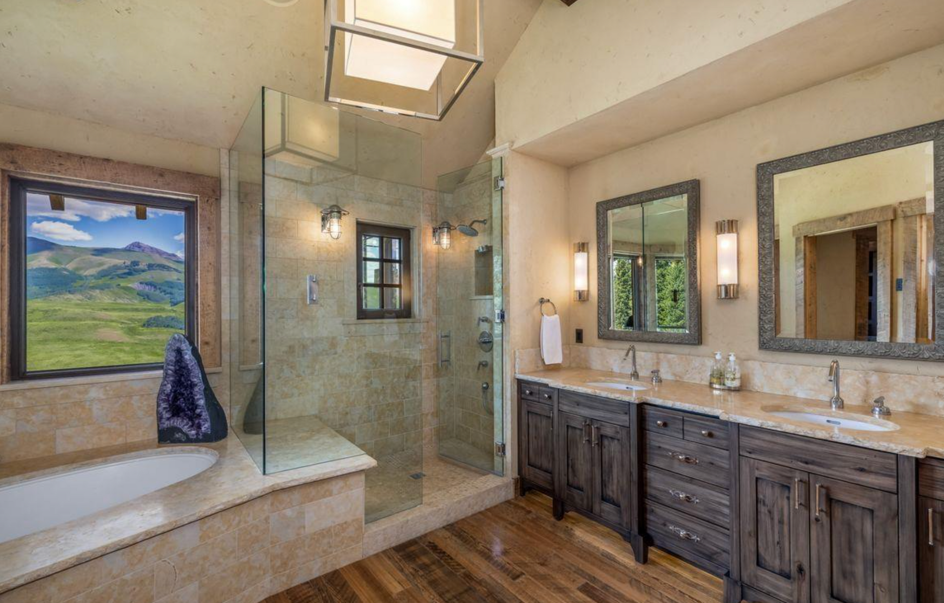 Luxury bathroom with freestanding tub, glass shower, double vanity, and large windows overlooking greenery