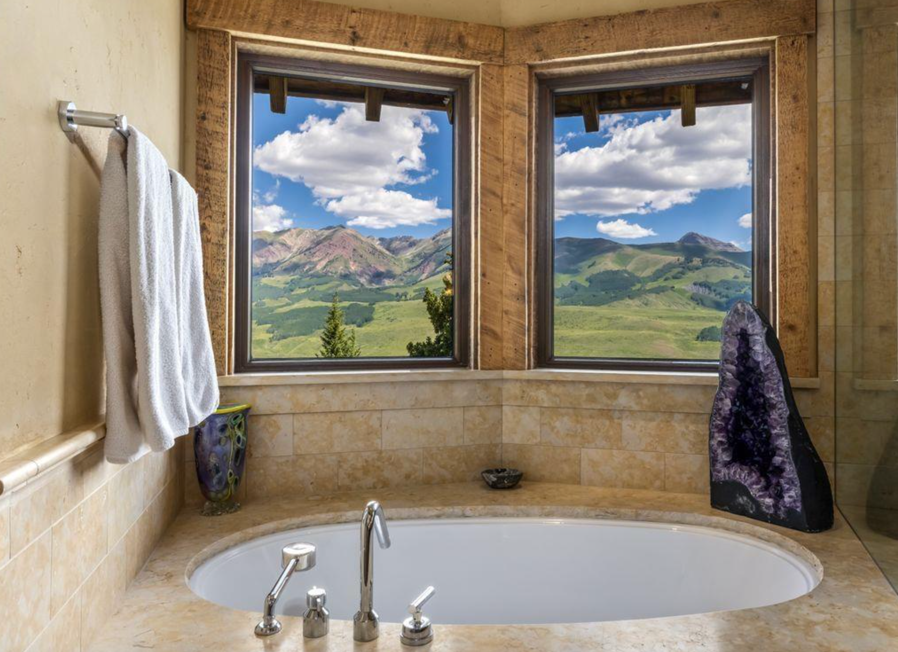 Bathroom with a bathtub and two windows overlooking a bright mountain valley.