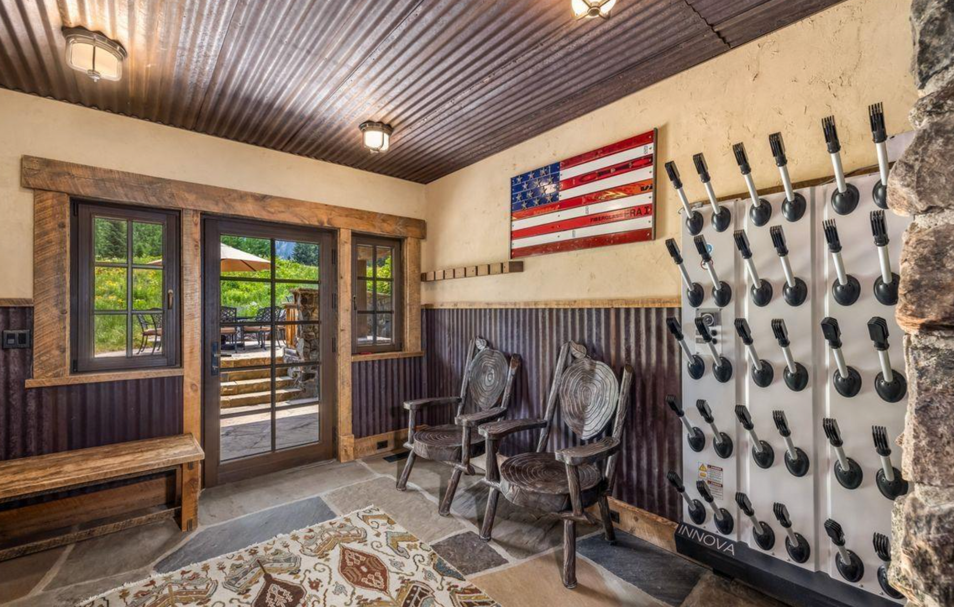 Rustic entryway with benches, chairs, an American flag, and wall-mounted decor