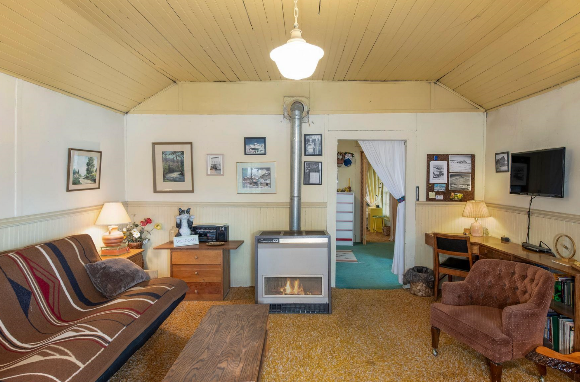 Cozy living room with brown sofa, armchair, TV, lamp, and doorway to a hallway