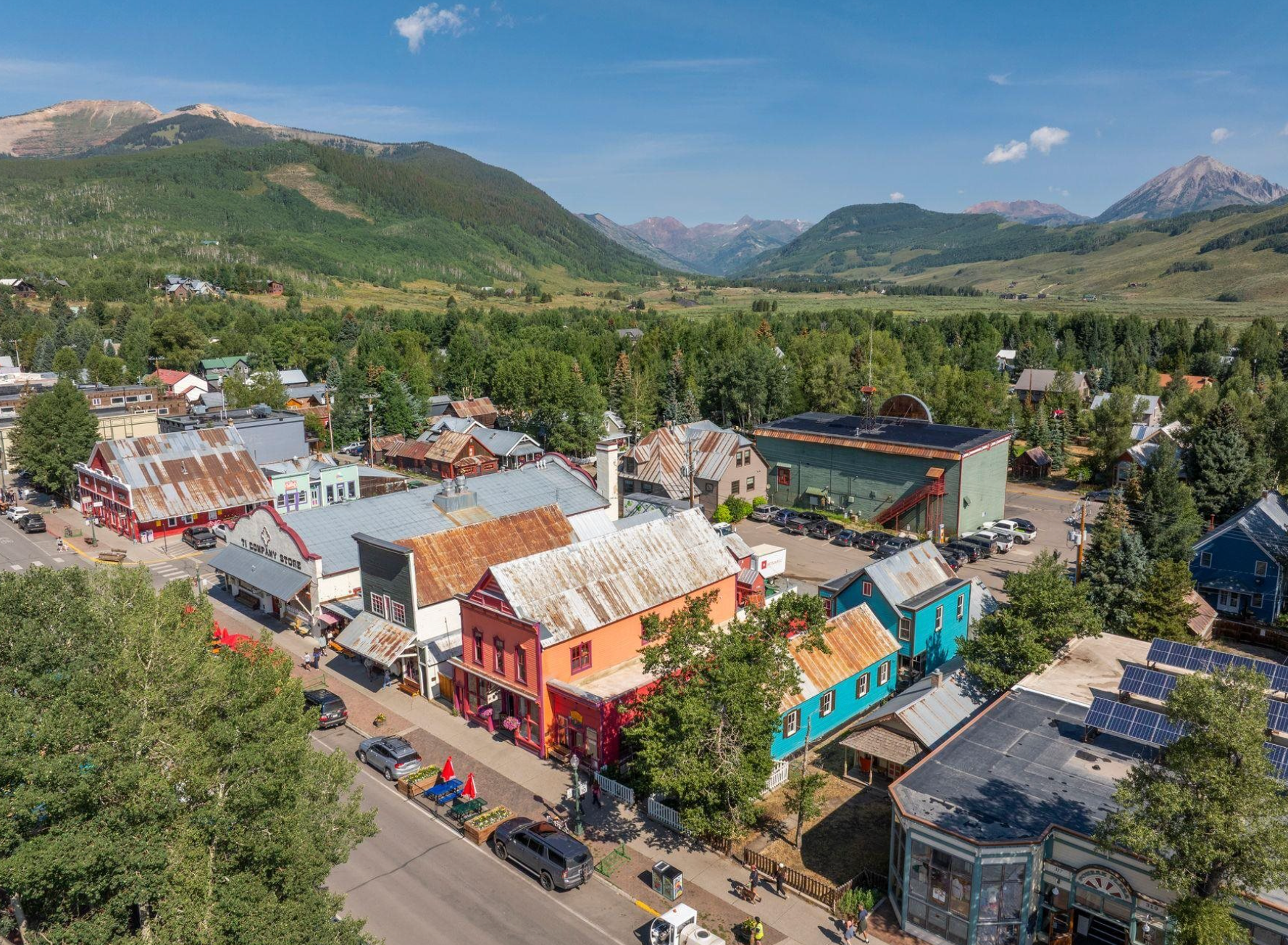 Colorful mountain town with red-roofed buildings and a scenic valley backdrop