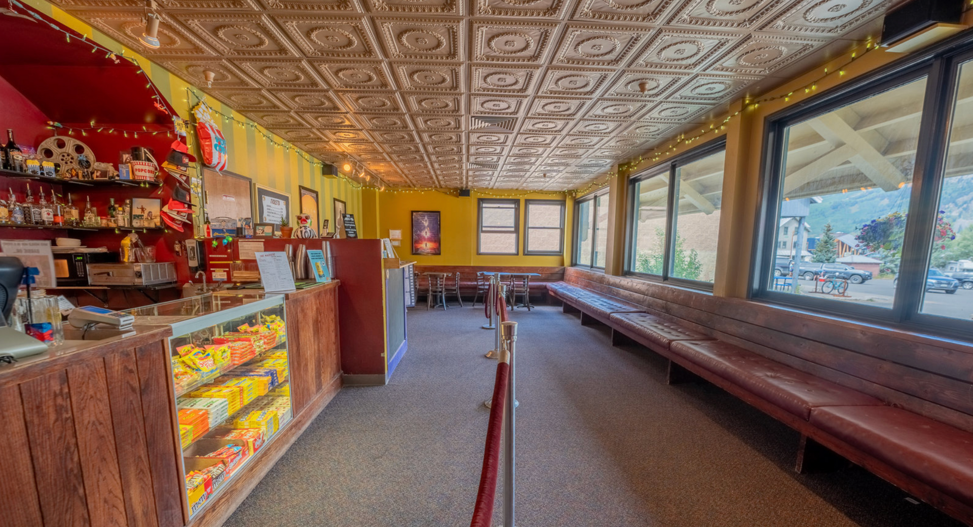 Empty diner with long red booths, wooden counter, and vintage ceiling tiles, lit by daylight through large windows