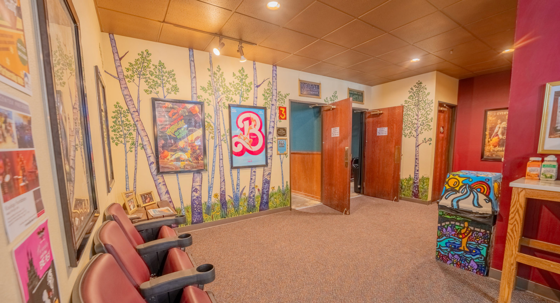 Colorful waiting room with chairs, artwork, and wooden doors under warm lighting