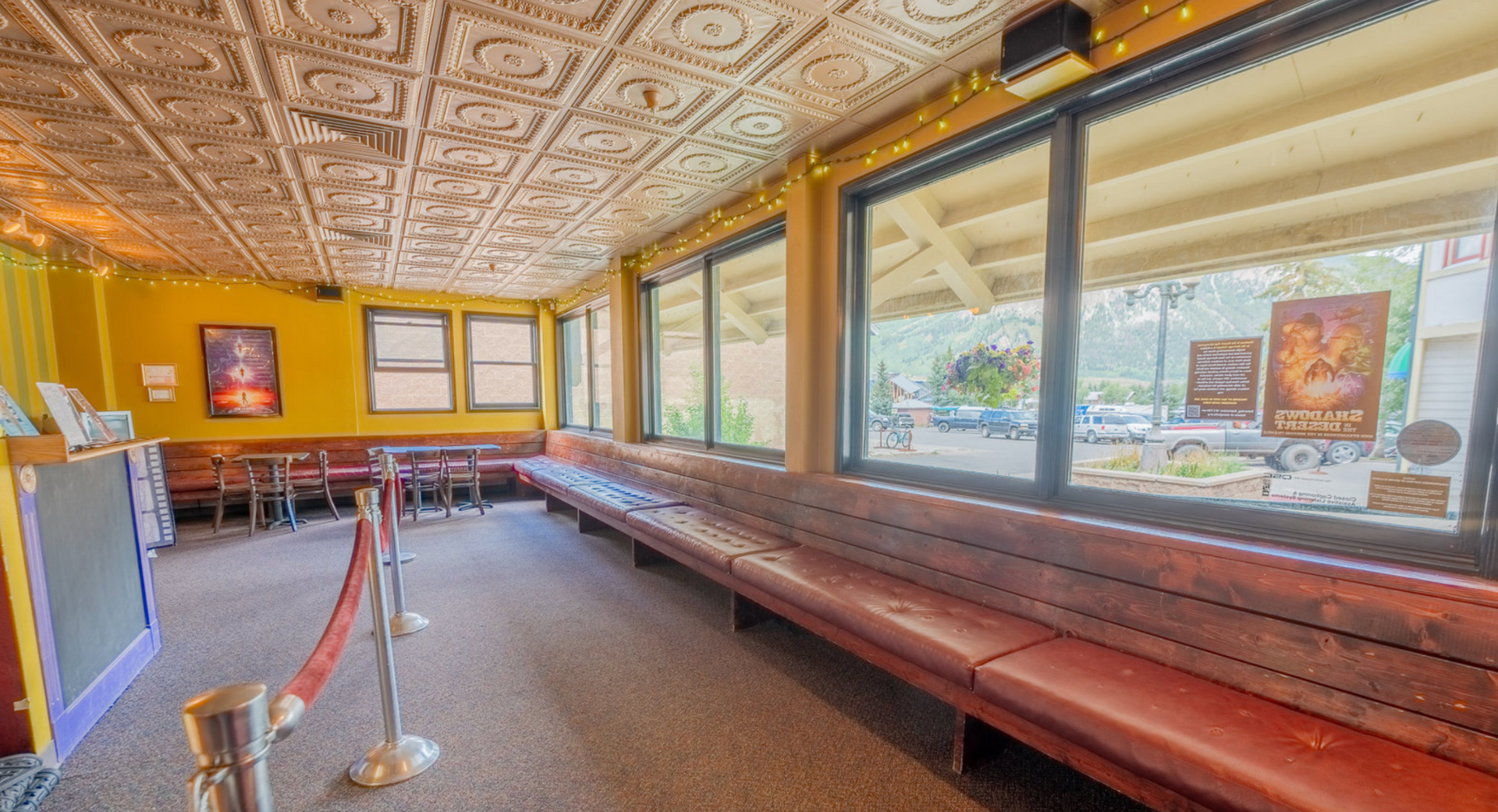 Empty retro diner interior with long red booth seating, ornate ceiling, and large front windows