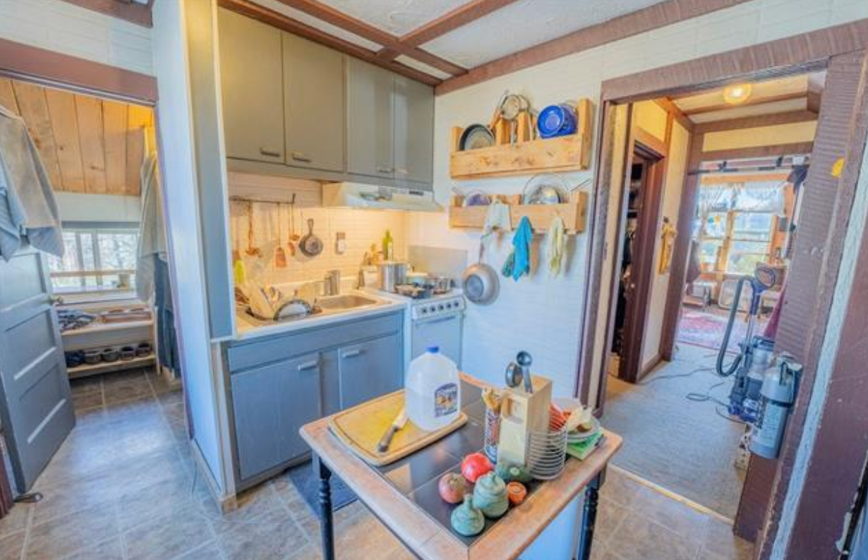 Compact kitchen with blue cabinets, a small island, and a doorway leading to a bright adjacent room.