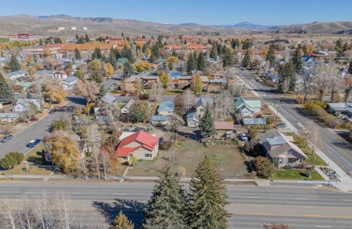 Aerial view of a quiet suburban neighborhood with houses, trees, and a road in autumn.