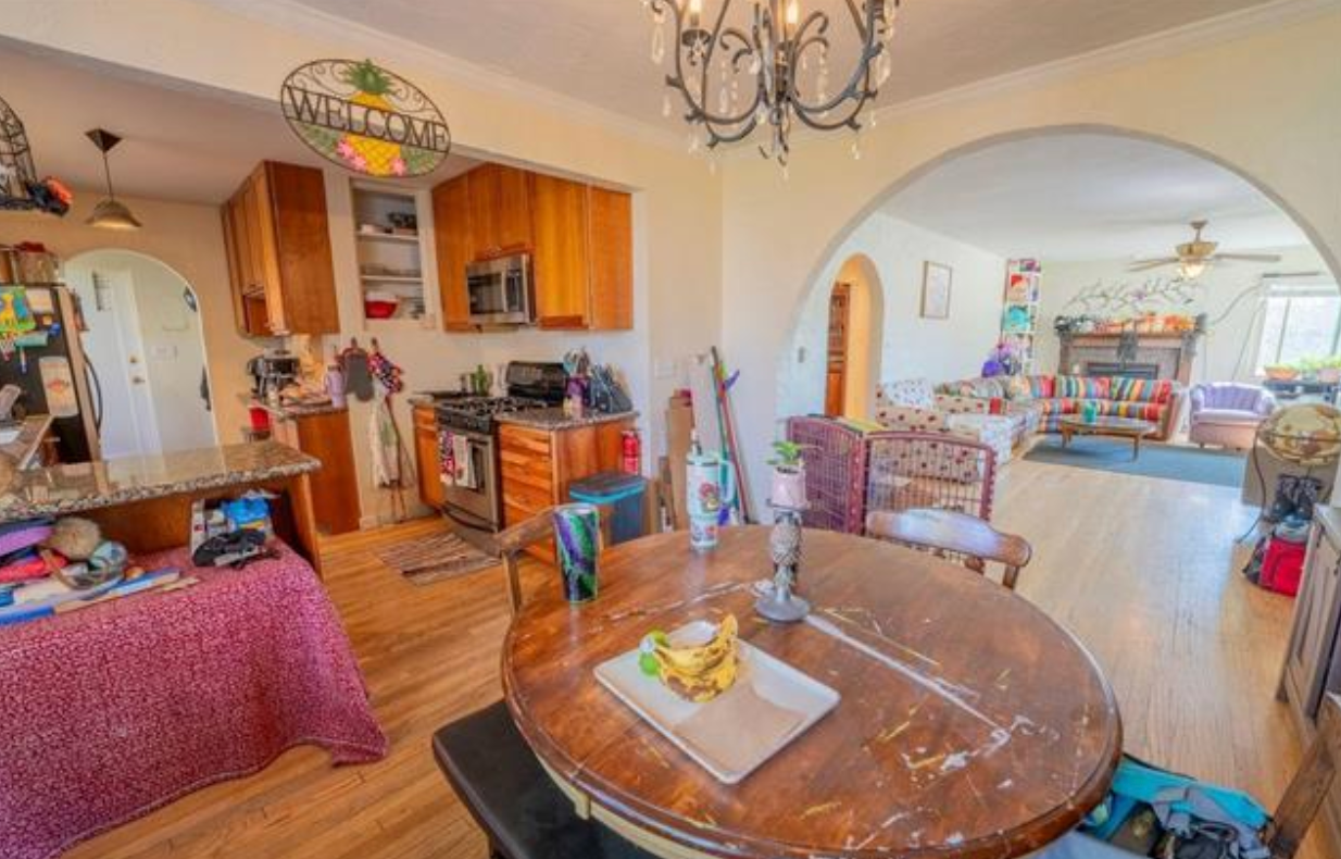 Warm kitchen and dining area with wood cabinets, round table, and archway to a bright living room