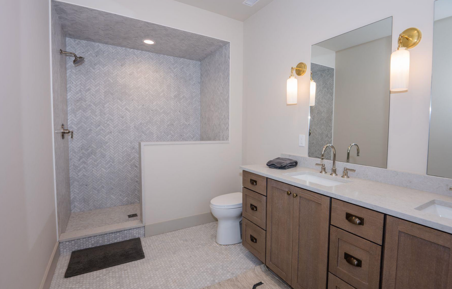 Modern bathroom with tiled shower, vanity, sink, mirror, and toilet in neutral tones