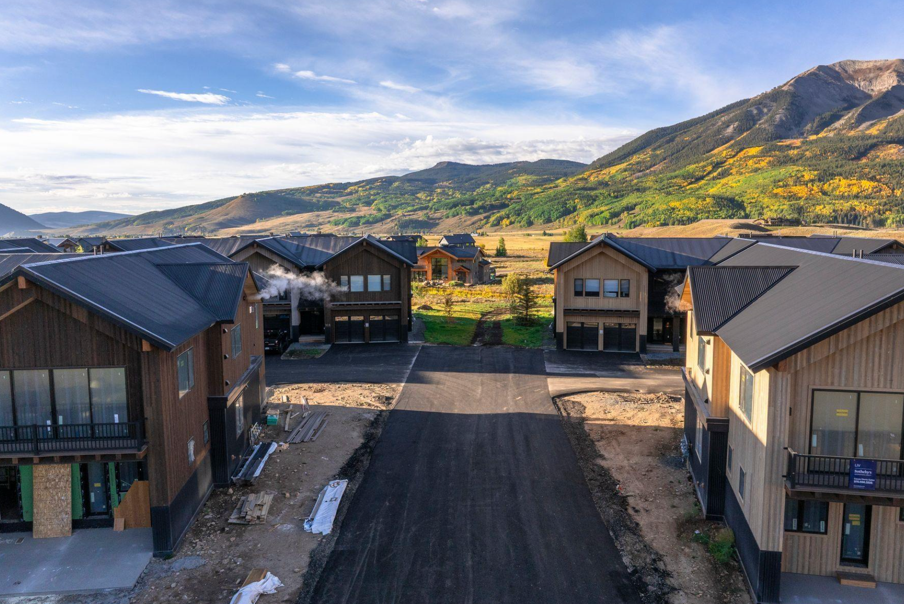 New homes under construction on a paved street with mountains in the background
