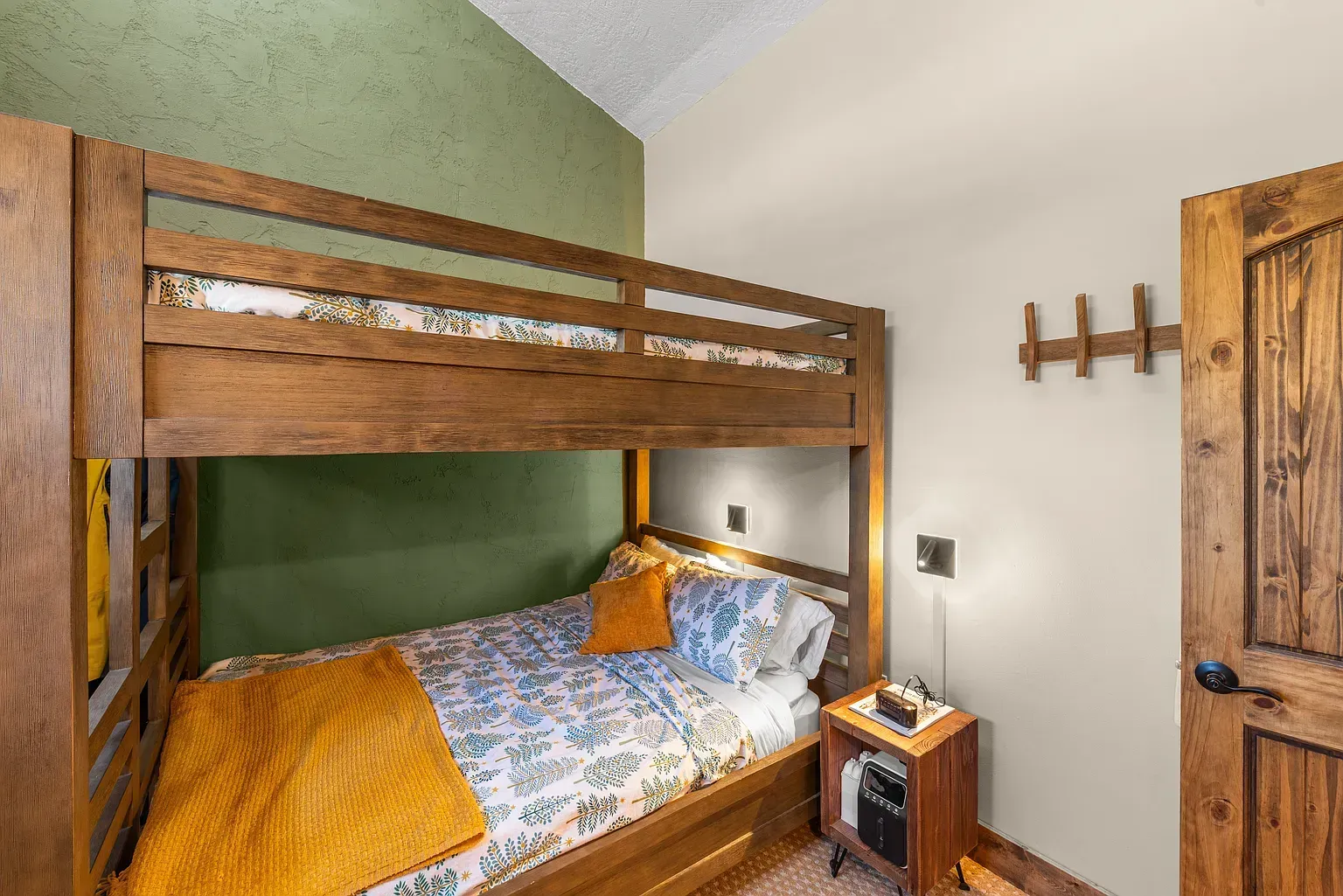 Wooden bunk bed with orange bedding in a cozy bedroom with green and white walls